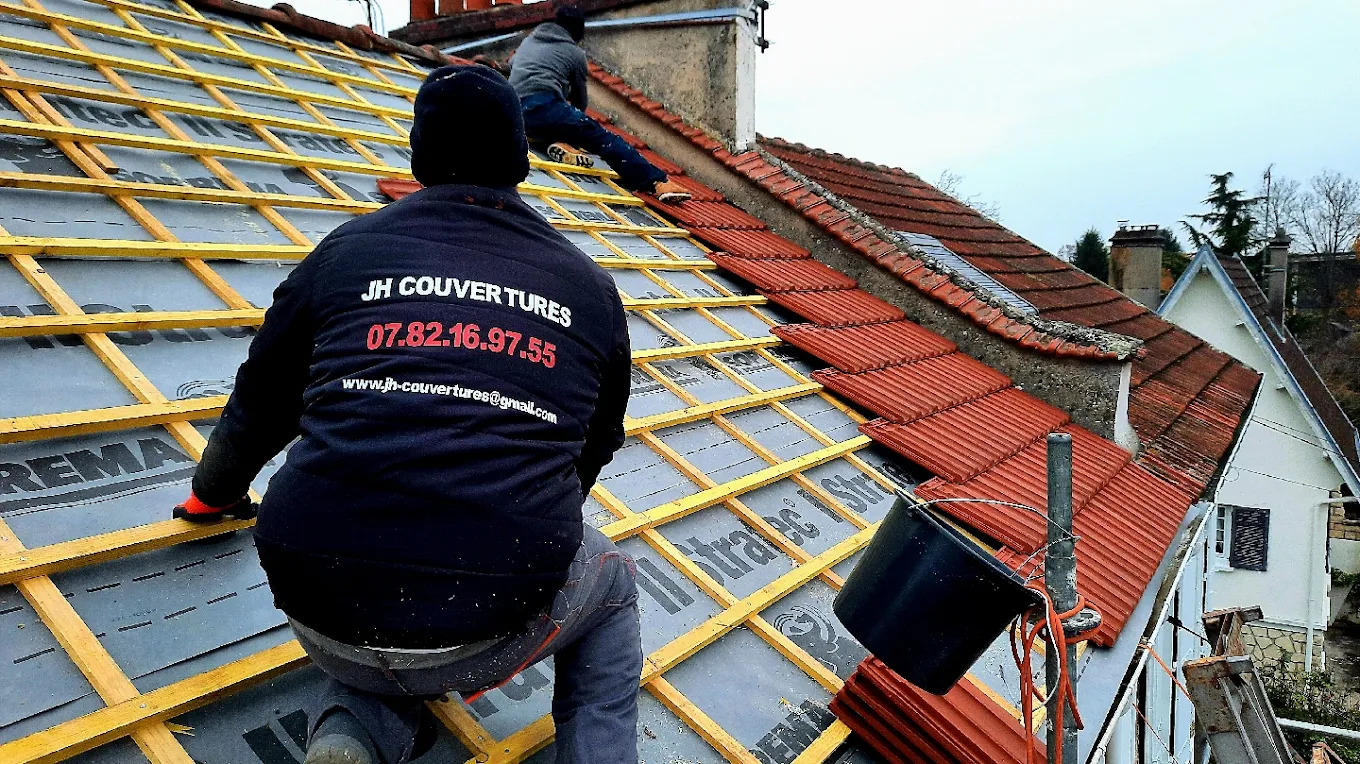 Couvreurs de JH Couvertures posant des tuiles sur une toiture en cours de rénovation à Chelles